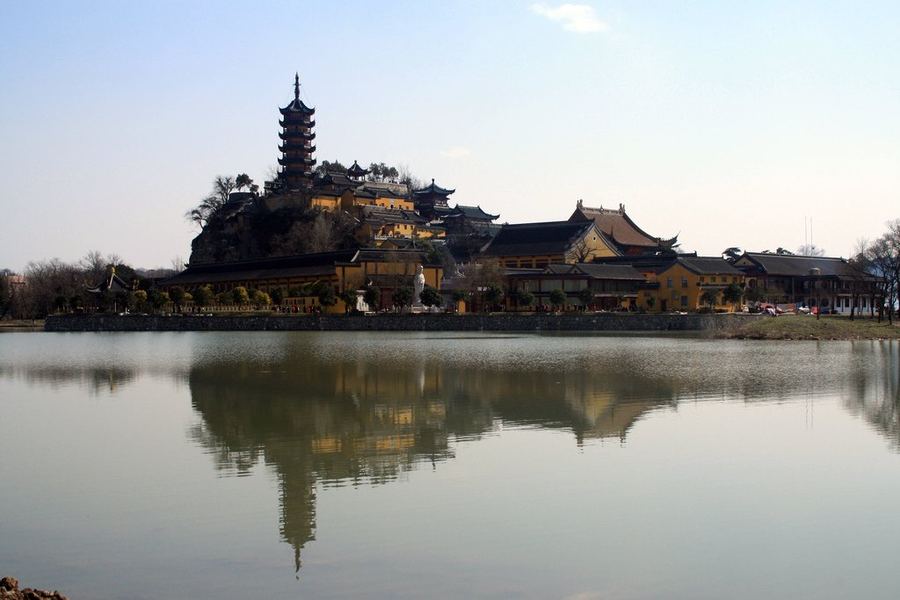 En Zhenjiang, la montaña de Jinshan se eleva sobre las aguas como un lugar suspendido entre historia y leyenda. En su cima se encuentra el templo asociado al monje Fa Hai, figura central de la antigua Leyenda de la Serpiente Blanca. La imagen recoge ese paisaje casi inmóvil, donde arquitectura, agua y reflejo parecen pertenecer al mismo espacio, evocando el límite difuso entre lo real, lo espiritual y lo mítico.